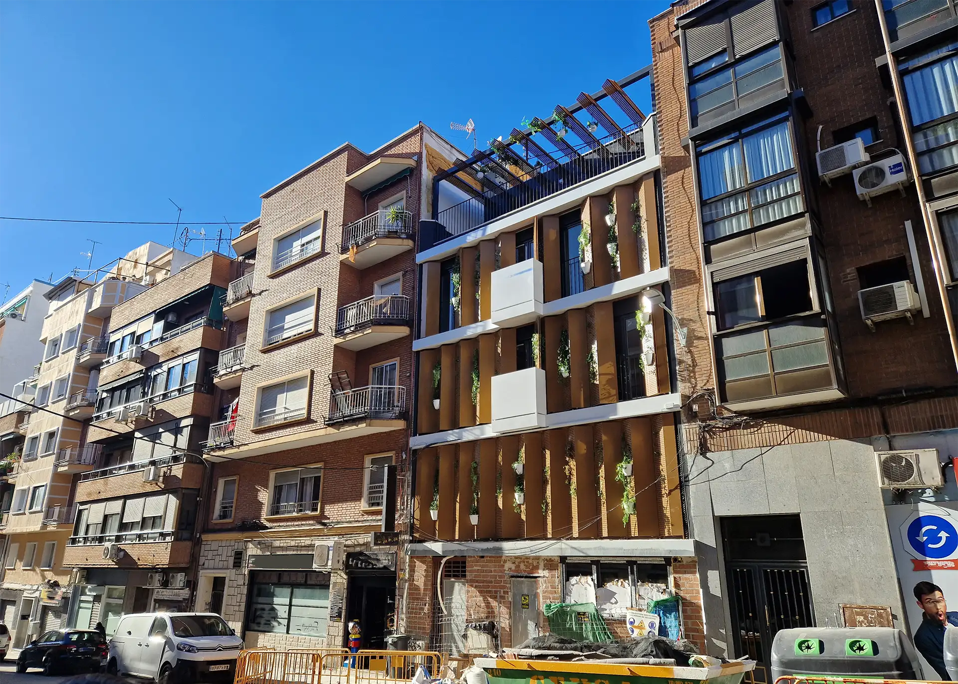 Imagen de la fachada completa desde un ángulo lateral, mostrando la integración de los paneles móviles y la vegetación, que redefine el paisaje urbano del barrio de Tetuán.